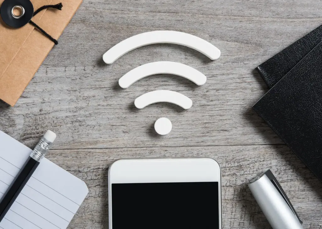 Draufsicht auf grauen Tisch mit Handy, darüber ein WLAN-Icon