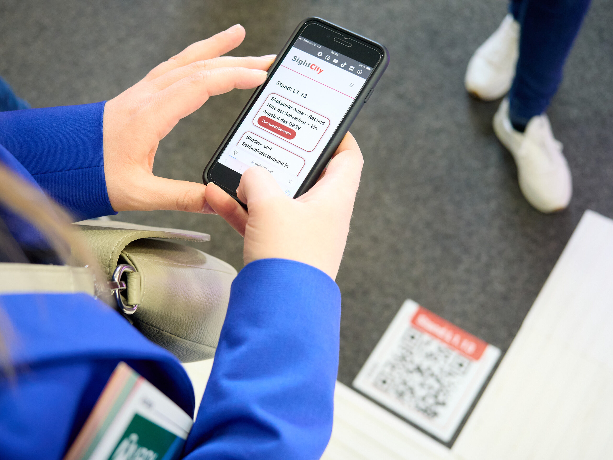 Im Blick auf ein Handy, das gerade einen QR-Code auf dem Boden abgescannt hat und die Informationen ausgelesen hat.
