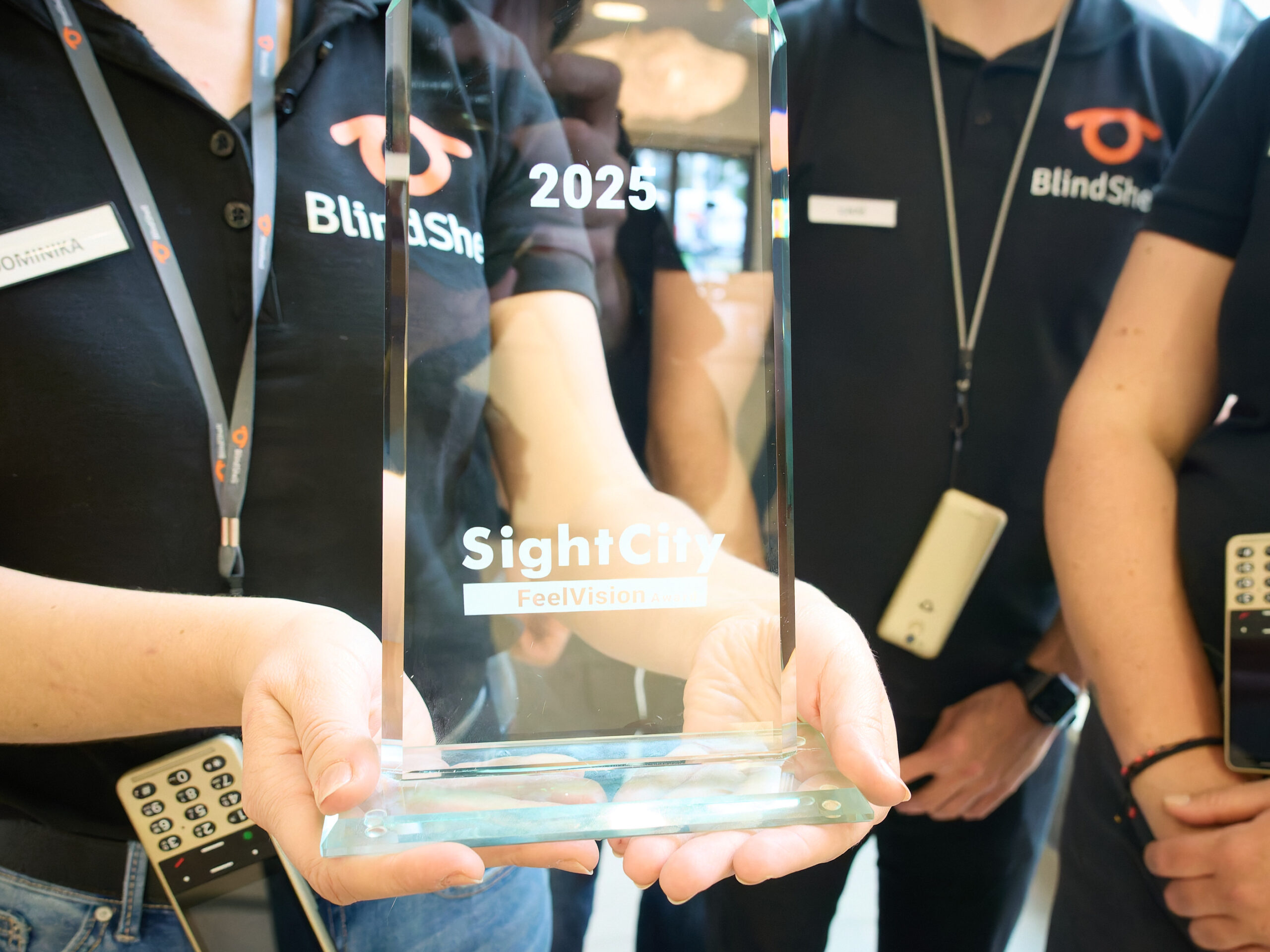 Hände halten einen Glaspokal mit SightCity FeelVision Award Prägung