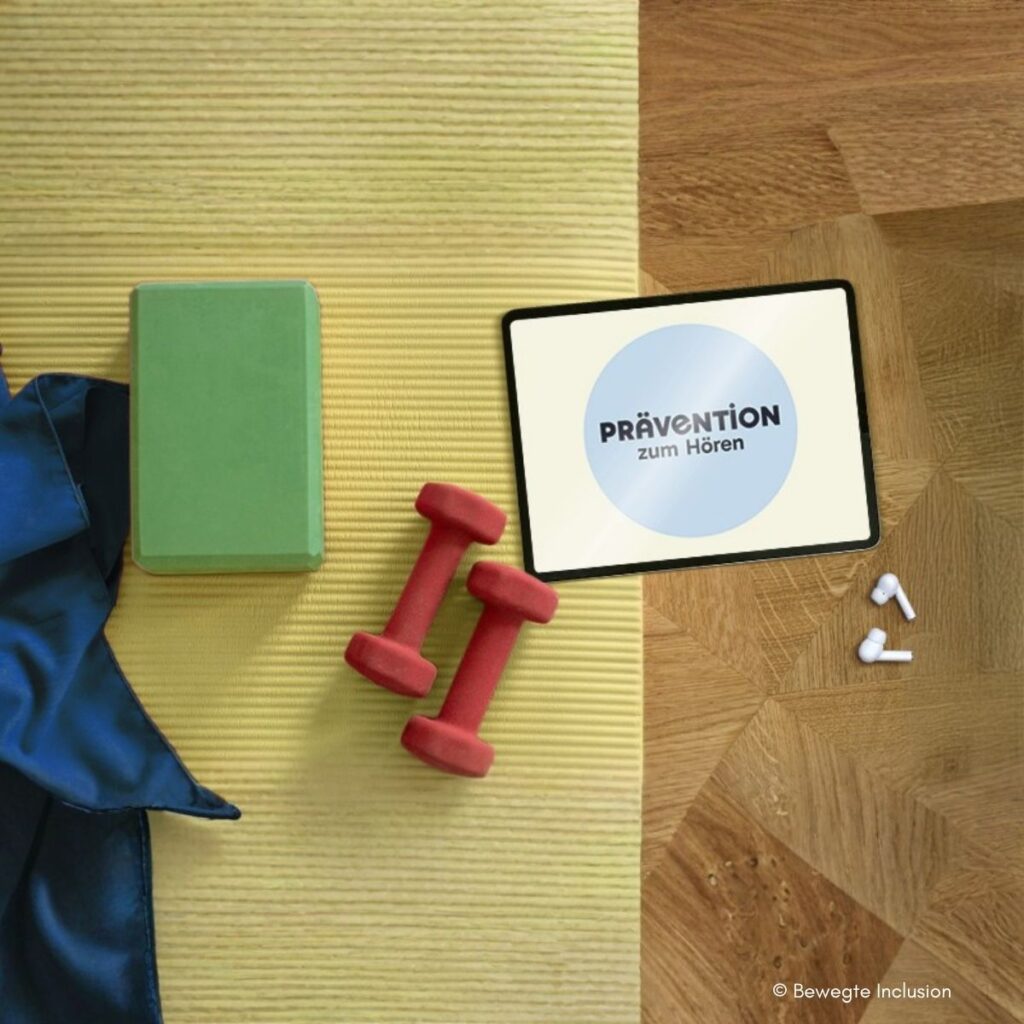Flatlay auf Yogamatte und Holzboden: Tablet mit Aufschrift „Prävention zum Hören", grüner Yogablock, zwei rote Hanteln, blaue Sporttasche und weiße In-Ear-Kopfhörer. © Bewegte Inclusion.