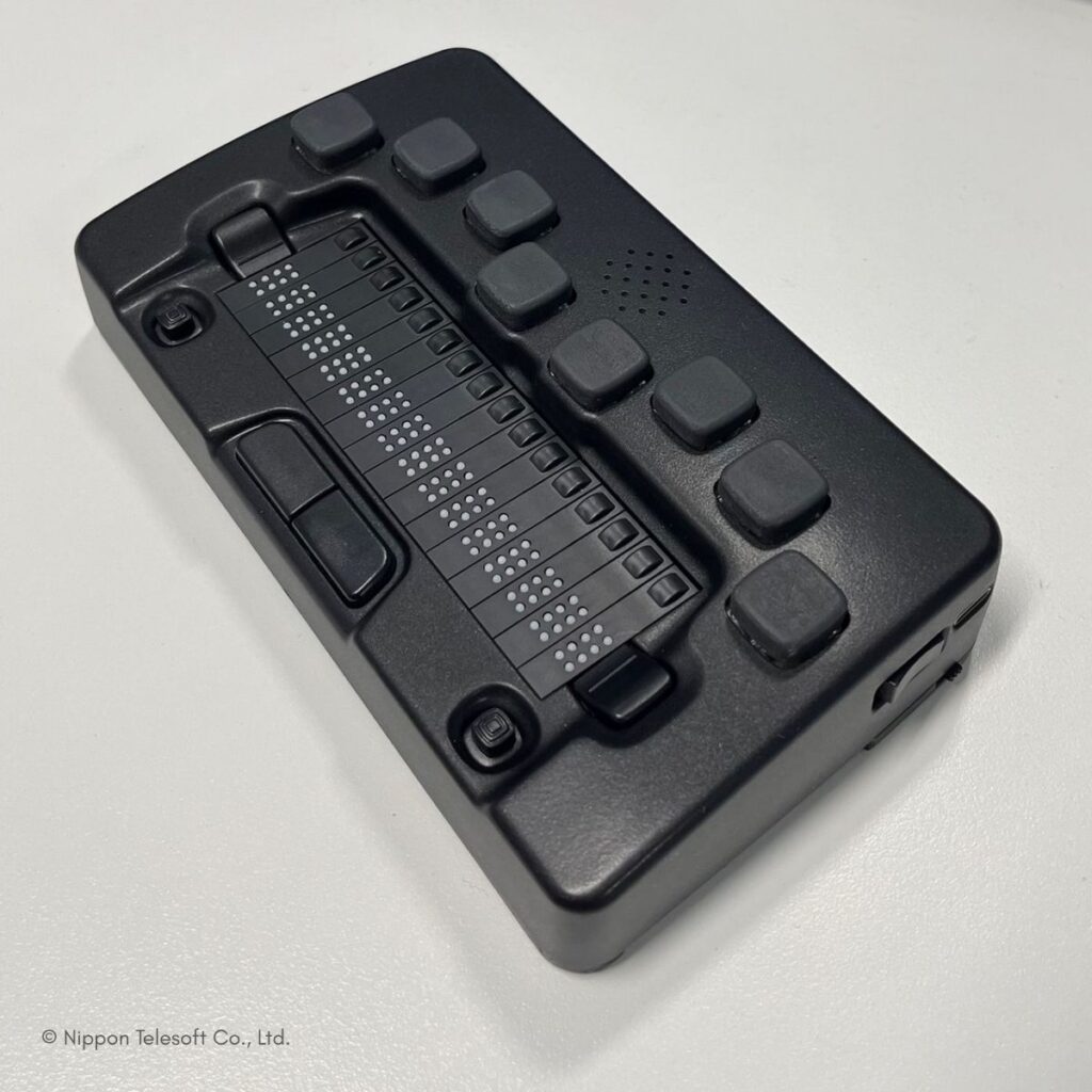 Kompaktes schwarzes Braille-Gerät von Nippon Telesoft mit mehreren Braillezeilen und Steuertasten, auf weißem Untergrund.