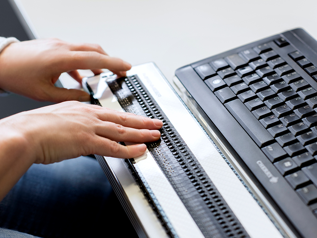 Photo Man working on laptop with BRAILLEX EL 40c Braille display
